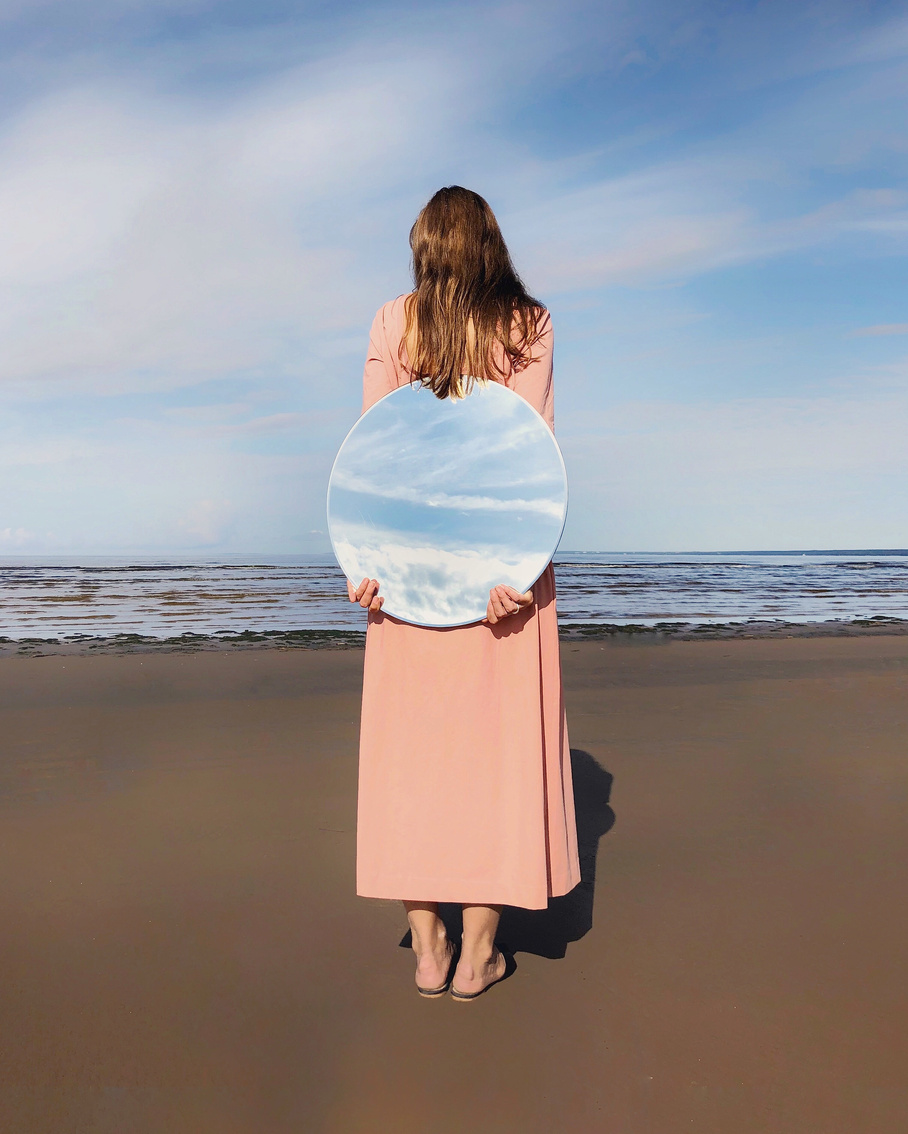 Woman Standing Beside Shore Holding Mirror on Her Back